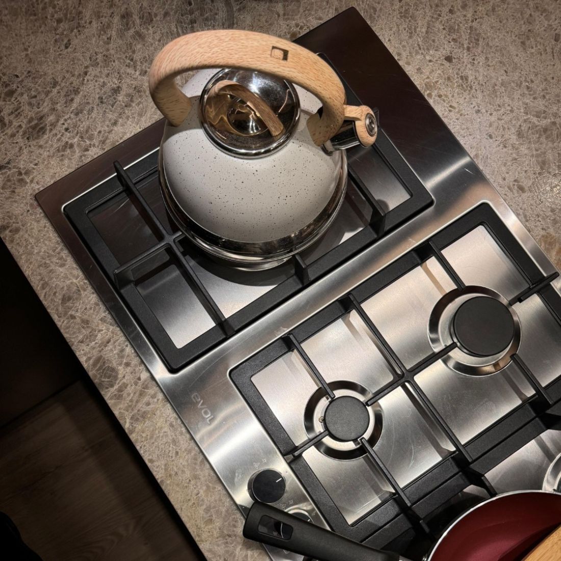 Cooktop Evol com chaleira em uma superfície de granito, destacando o painel e o design elegante.