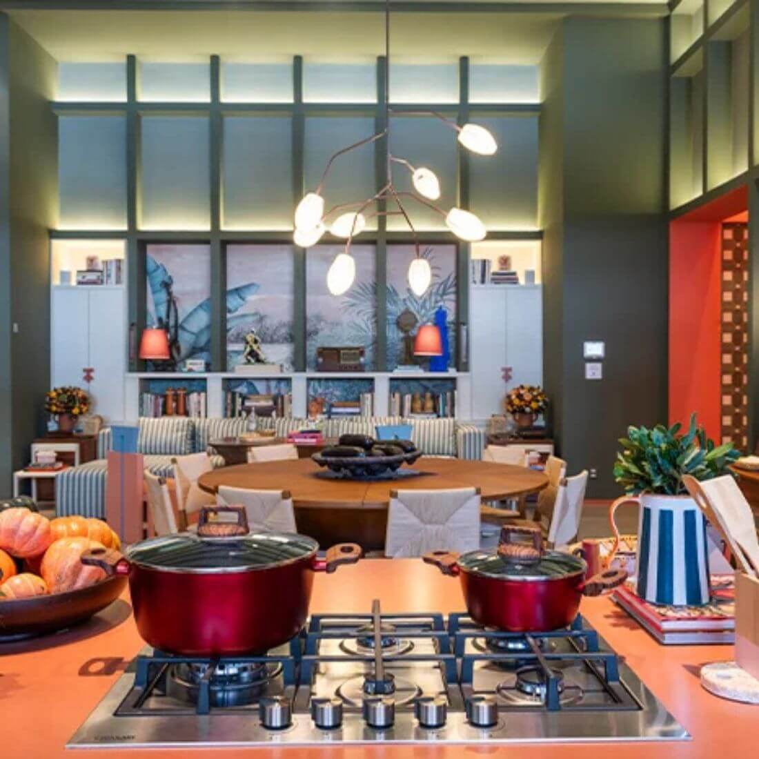 Cozinha moderna com cooktop a gás e panelas vermelhas em um ambiente acolhedor e bem decorado.