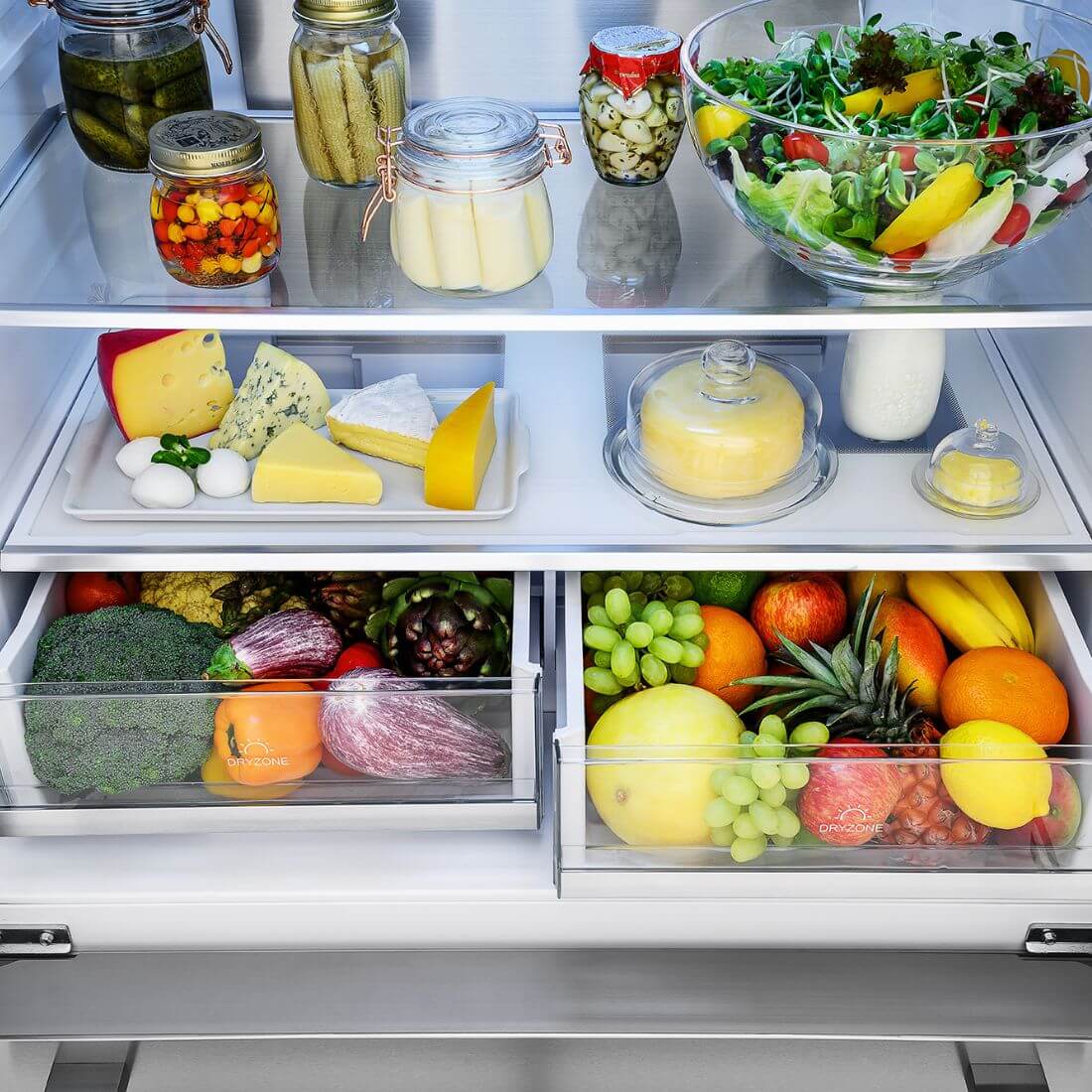Interior do Refrigerador Tecno Professional com frutas, legumes, laticínios e conservas organizados em prateleiras de aço inox.