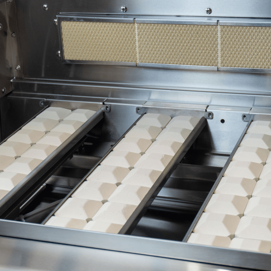 Interior view of a gas grill showing ceramic briquettes for efficient heat distribution.