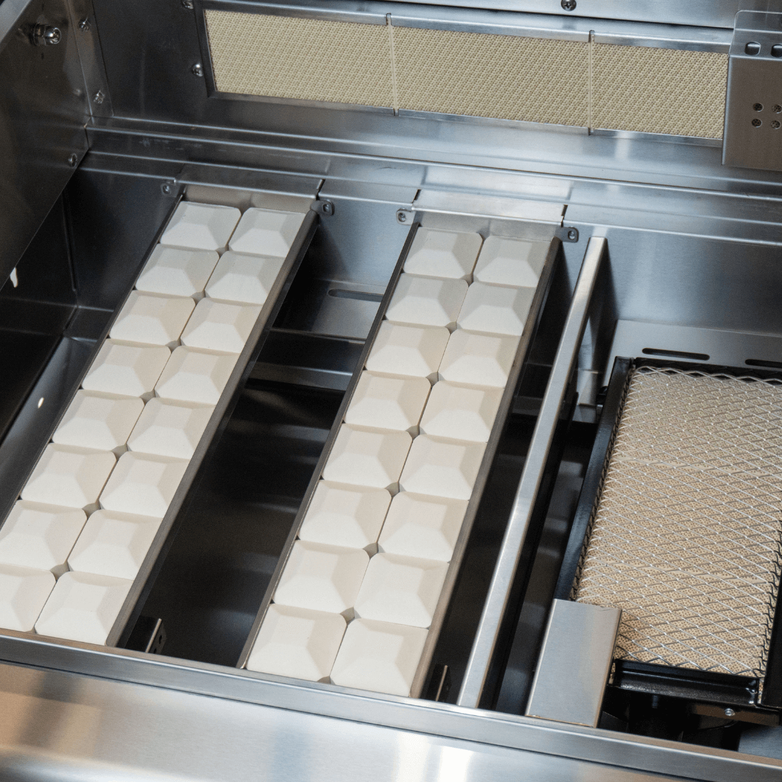 Interior view of Cuisinart Arkton gas grill with ceramic heat plates and grease tray for efficient cooking.