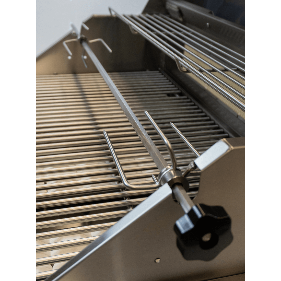Interior view of Cuisinart Arkton gas grill with a rotisserie spit and stainless steel grates.