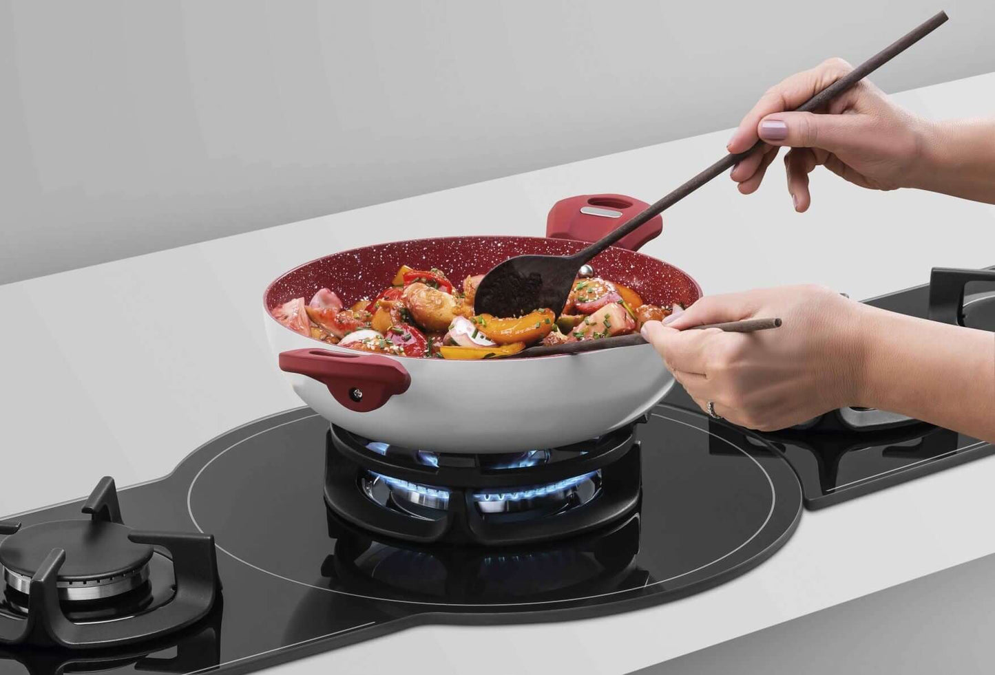 Pessoa cozinhando em um cooktop com panela colorida, preparando uma refeição deliciosamente variada.