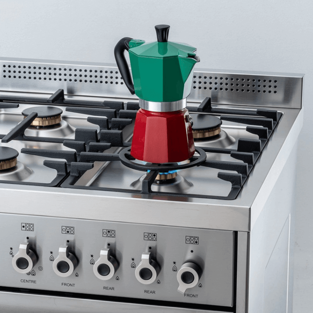 Cafeteira italiana colorida sobre fogão a gás de 6 bocas, destacando queimadores e botões em inox.
