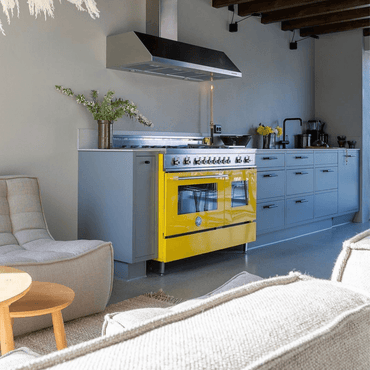 Cozinha moderna com fogão Bertazzoni amarelo de 6 bocas, móveis cinza e decoração minimalista.