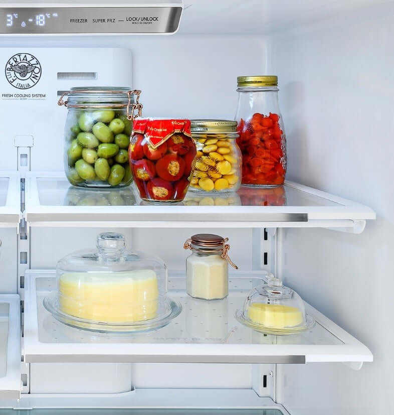 Interior do refrigerador Bertazzoni com compotas, azeitonas e sobremesas. Organização prática e elegante das prateleiras.