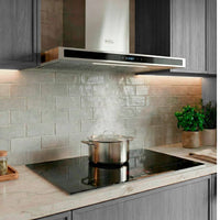 Coifa Evol Sigma de Parede 90cm inox com painel vidro preto instalada sobre cooktop, extraindo vapor de panela e iluminação embutida