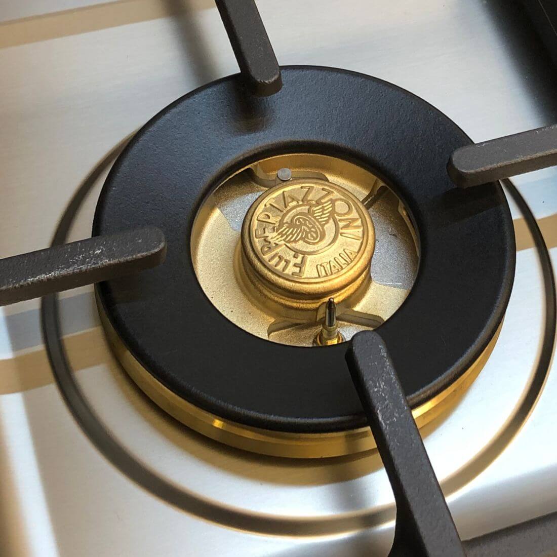 Detalhe do queimador a gás em latão do cooktop Bertazzoni, destacando design e eficiência.