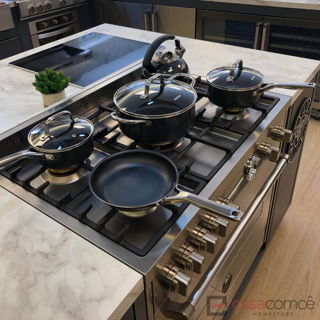 Conjunto de panelas sobre fogão Bertazzoni Master 5 bocas em inox, com tampas brilhantes e superfície de mármore.