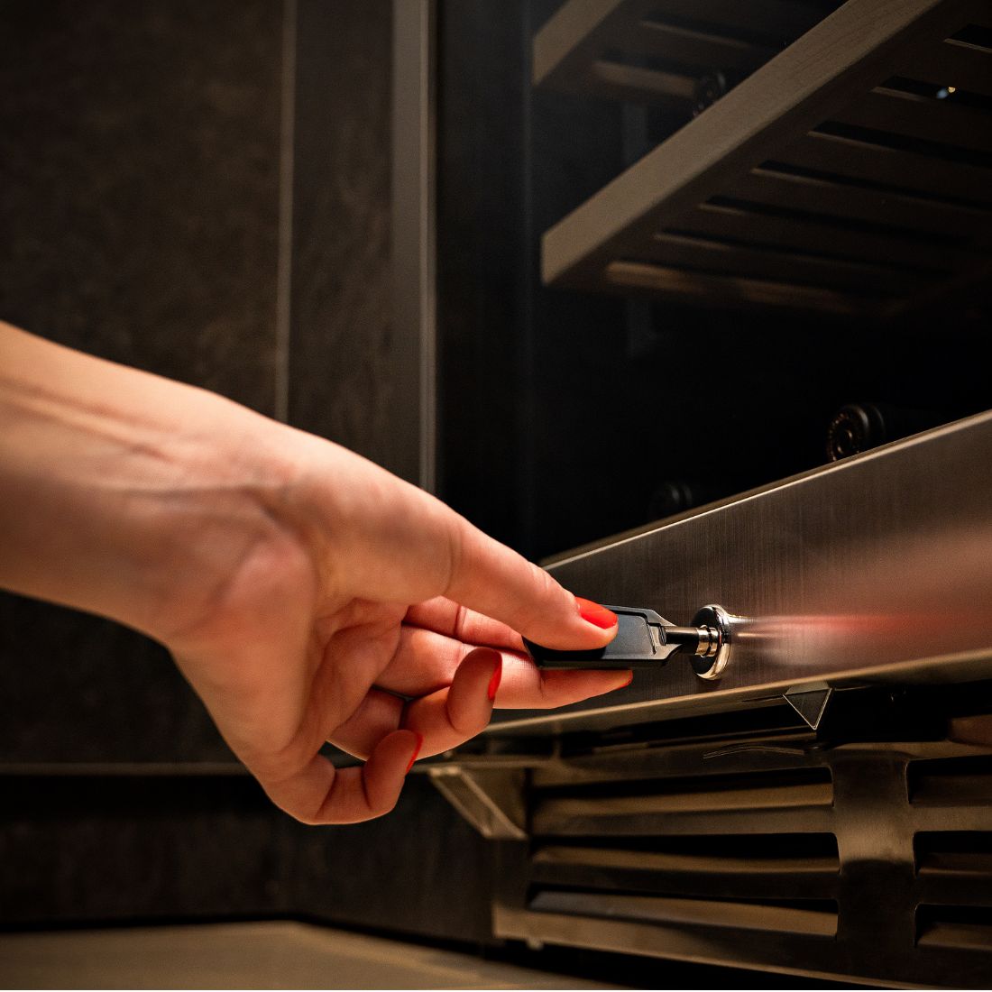 Adega de Vinhos Debacco 94 Garrafas Inox 60cm mostrando mão com chave abrindo adega climatizada em inox embutida, acabamento sofisticado