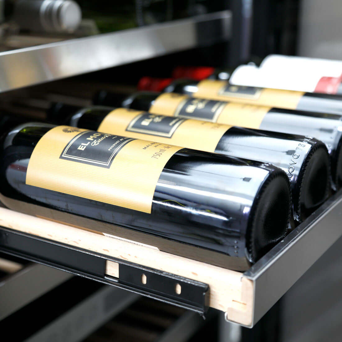 Garrafa de vinho em adega CrissAir, destacando rótulo amarelo e interior bem iluminado.