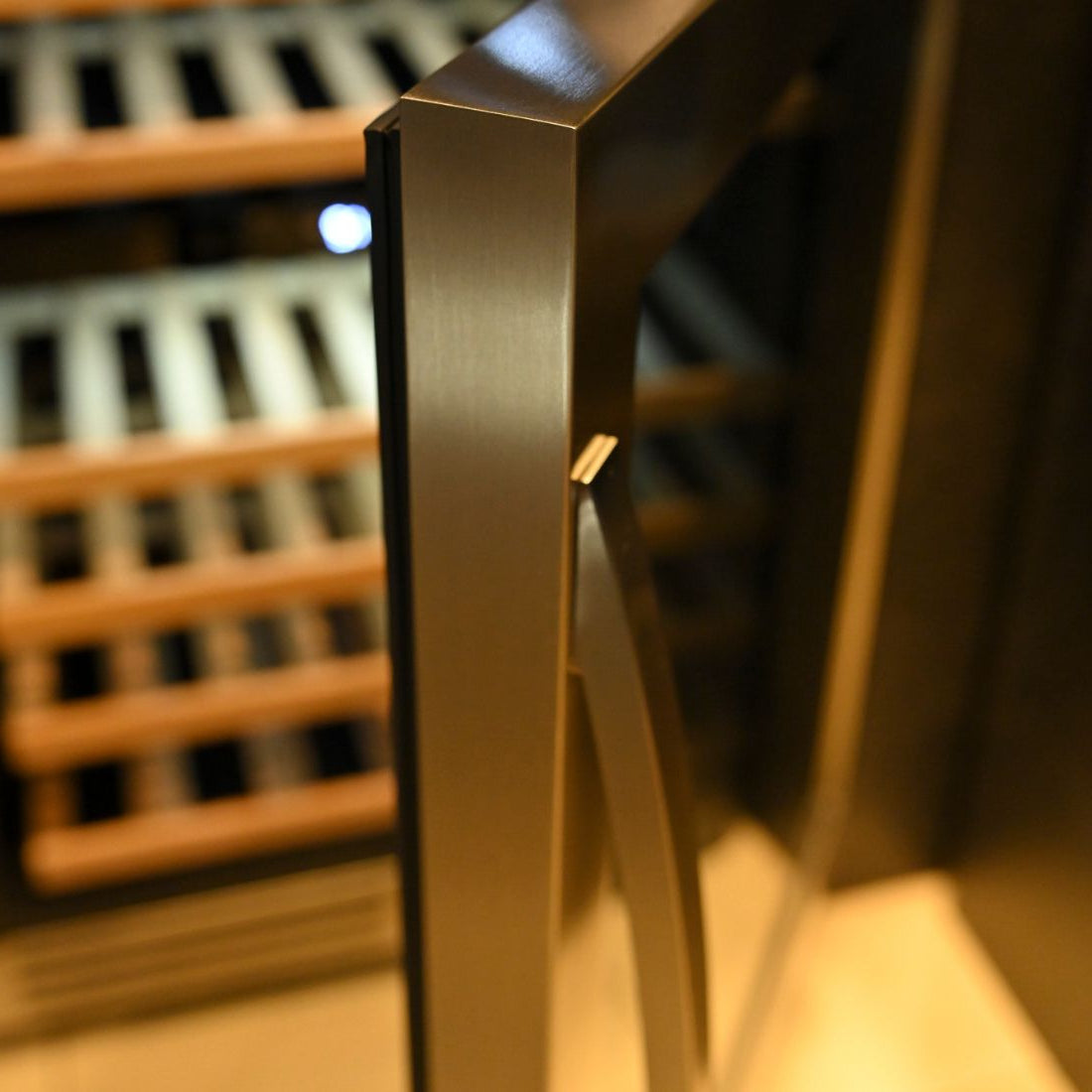 Imagem da porta da Adega Debacco 46 Garrafas Inox 60cm - Abertura Direita, com detalhe em inox e prateleiras visíveis.