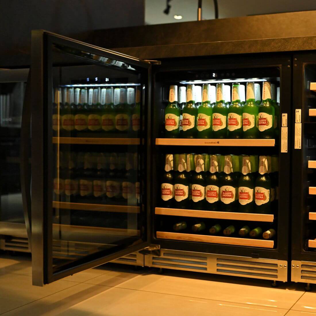 Cervejeira Debacco 145 Litros Inox 60cm - Abertura Esquerda com acabamento inox, porta de vidro duplo aberta e prateleiras com cervejas exibidas
