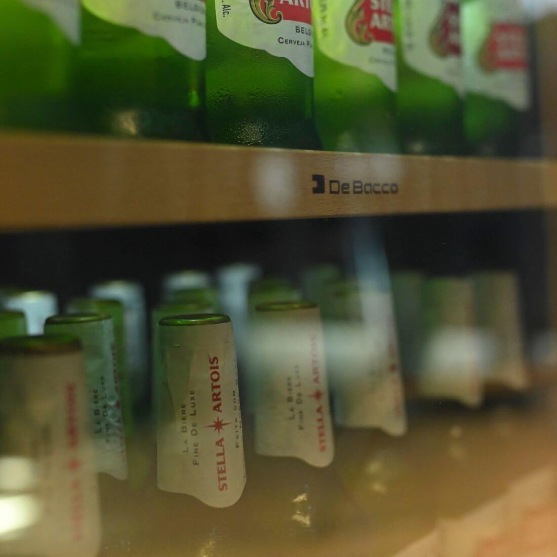 Cervejeira Debacco 145 Litros Inox 60cm - Abertura Esquerda com prateleiras em metal e frente em madeira nobre, porta de vidro exibindo garrafas