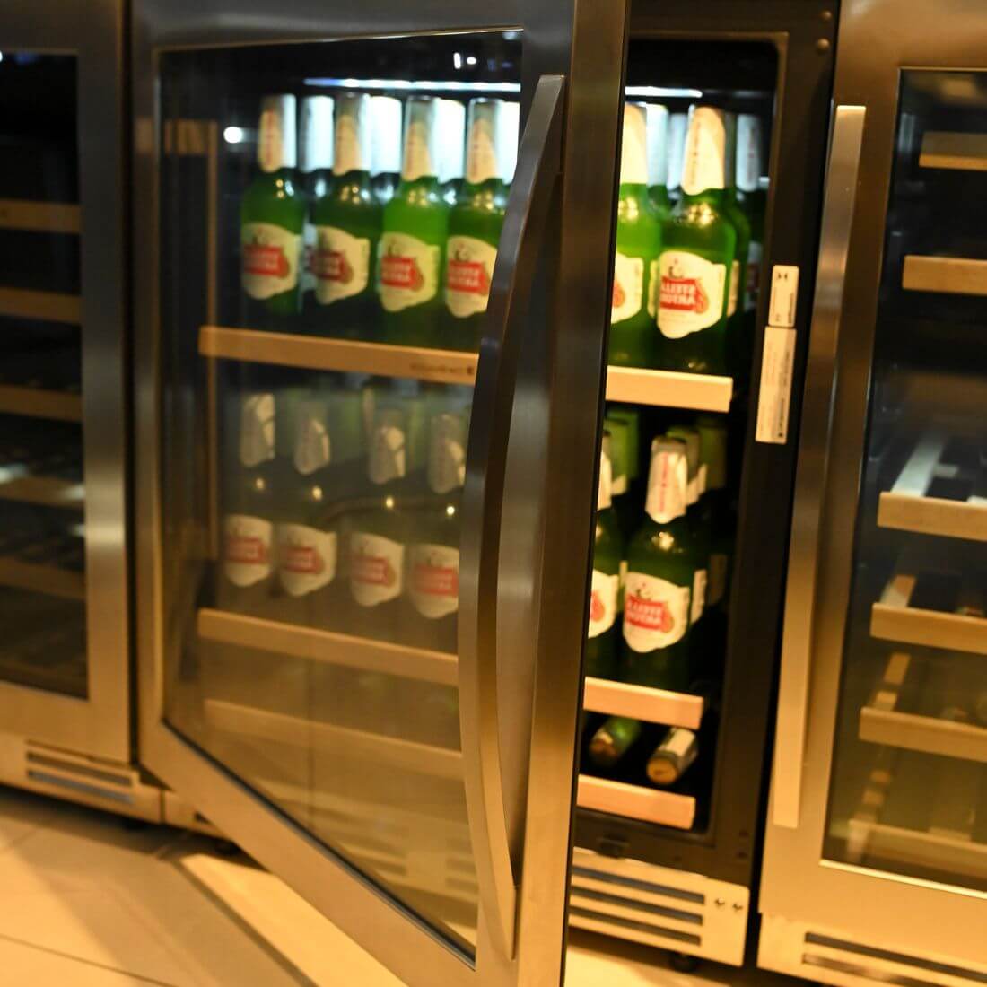 Cervejeira Debacco 145 Litros Inox 60cm - Abertura Esquerda: cervejeira com acabamento inox, porta de vidro duplo aberta, prateleiras em metal e iluminação interna