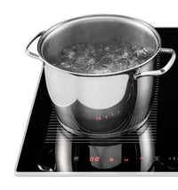 Cooktop de Indução Tecno 4 Zonas 60cm: cooktop de indução com vitrocerâmico preto, acabamento inox e painel touch, panela grande em uso