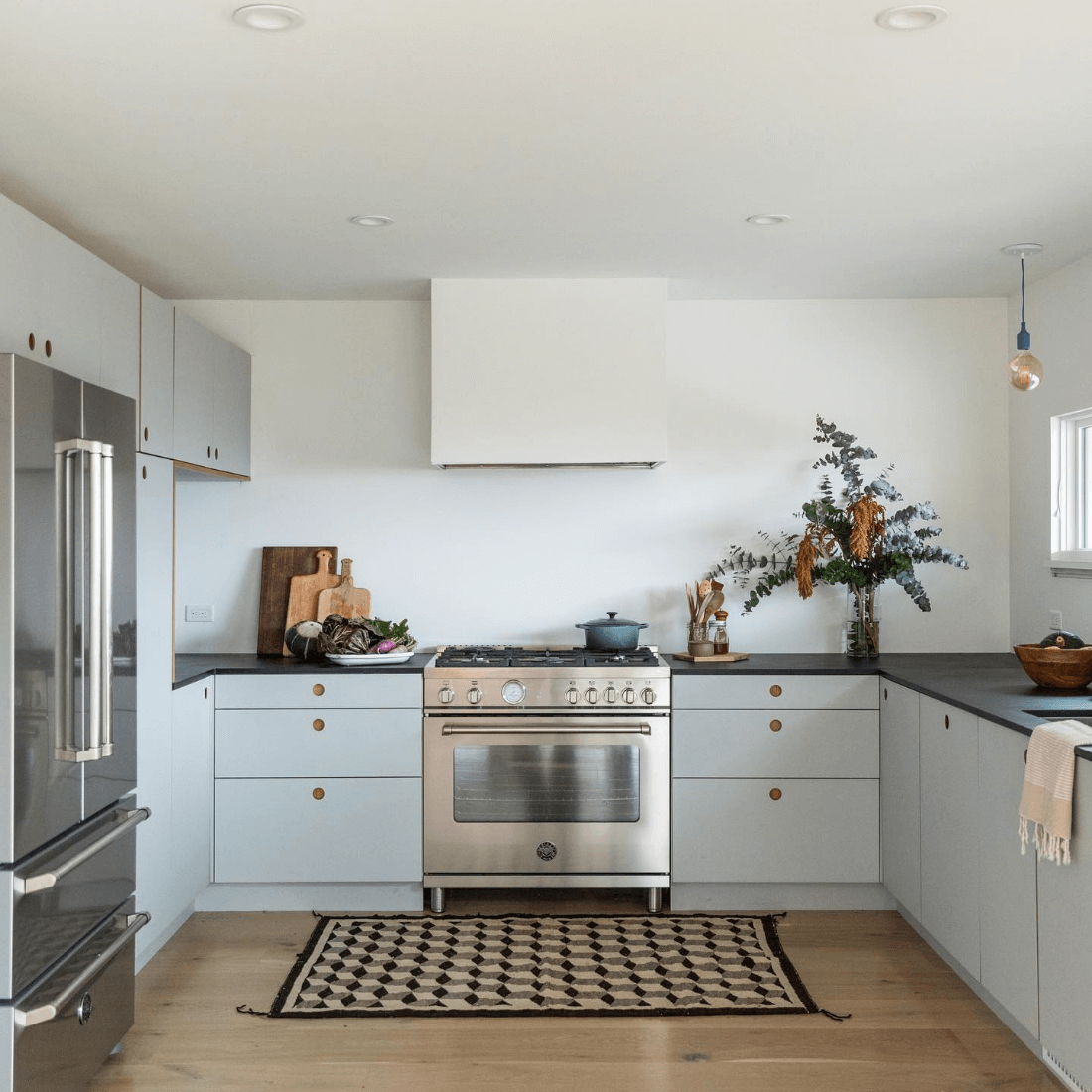 Cozinha moderna com fogão inox, armários cinza e decoração minimalista.