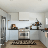 Cozinha moderna com fogão inox, armários cinza e decoração minimalista.