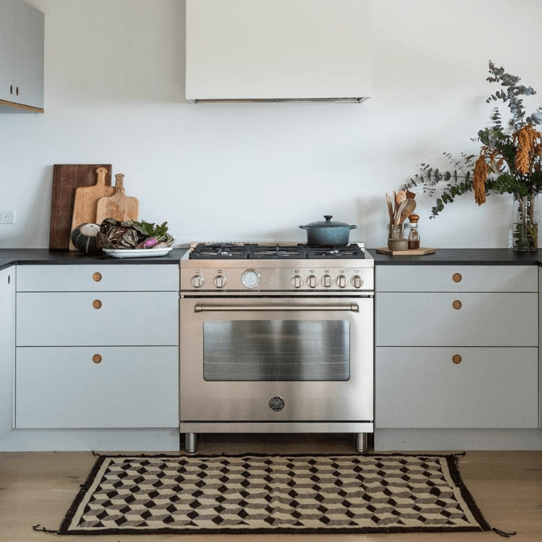 Fogão Bertazzoni Master inox 5 bocas em uma cozinha moderna com armários cinzas e decoração rústica.