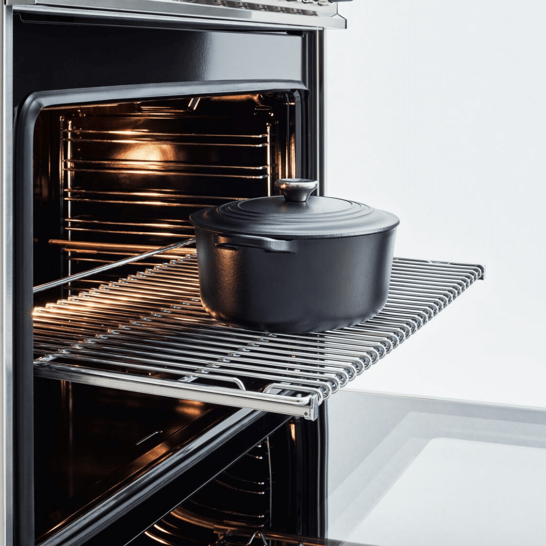 Panela preta no interior do forno Bertazzoni, iluminada e com prateleira de inox.