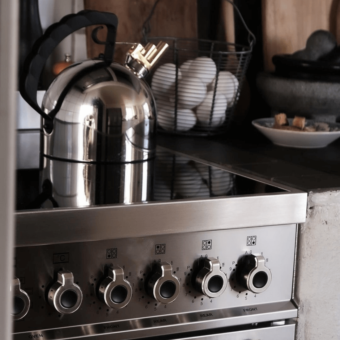 Chaleira inox sobre fogão Bertazzoni Professional com mesa de indução e knobs de controle.