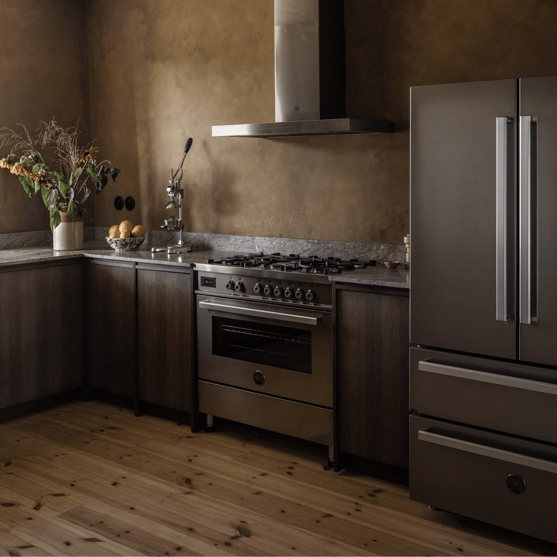 Cozinha moderna com fogão Bertazzoni, armários em madeira e eletrodomésticos em inox.
