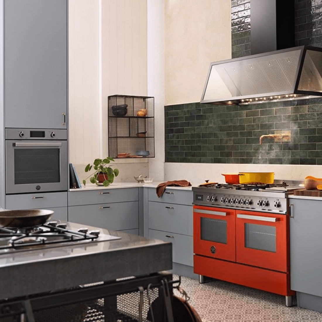 Cozinha moderna com fogão Bertazzoni laranja de 6 bocas e forno elétrico, armários em tons de azul e detalhes em verde.