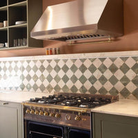 Coifa Elica de Parede New Calabria Vintage 91cm Inox instalada na parede em inox acetinado, formato piramidal inclinado com duto e barra dourada visível