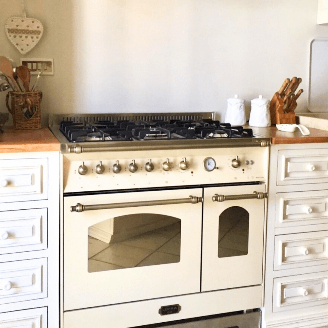 Fogão Lofra Dolcevita Branco 90cm 5 Bocas Forno Duplo Elétrico 106L em piso branco creme, 5 bocas com grade ferro fundido, painéis e puxadores estilo italiano