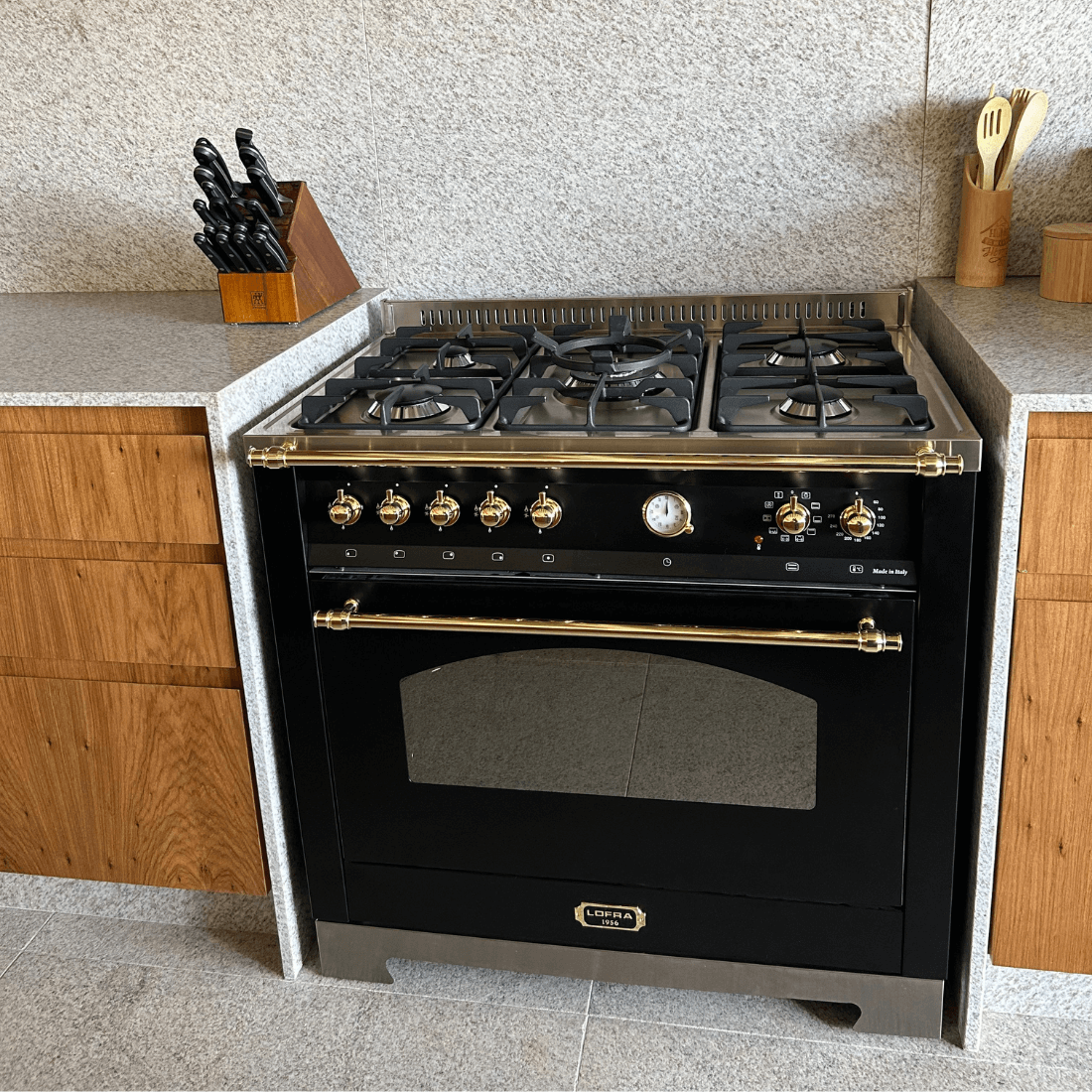 Fogão Lofra Vintage Dolcevita 5 bocas preto em cozinha moderna com acabamento em madeira e granito.