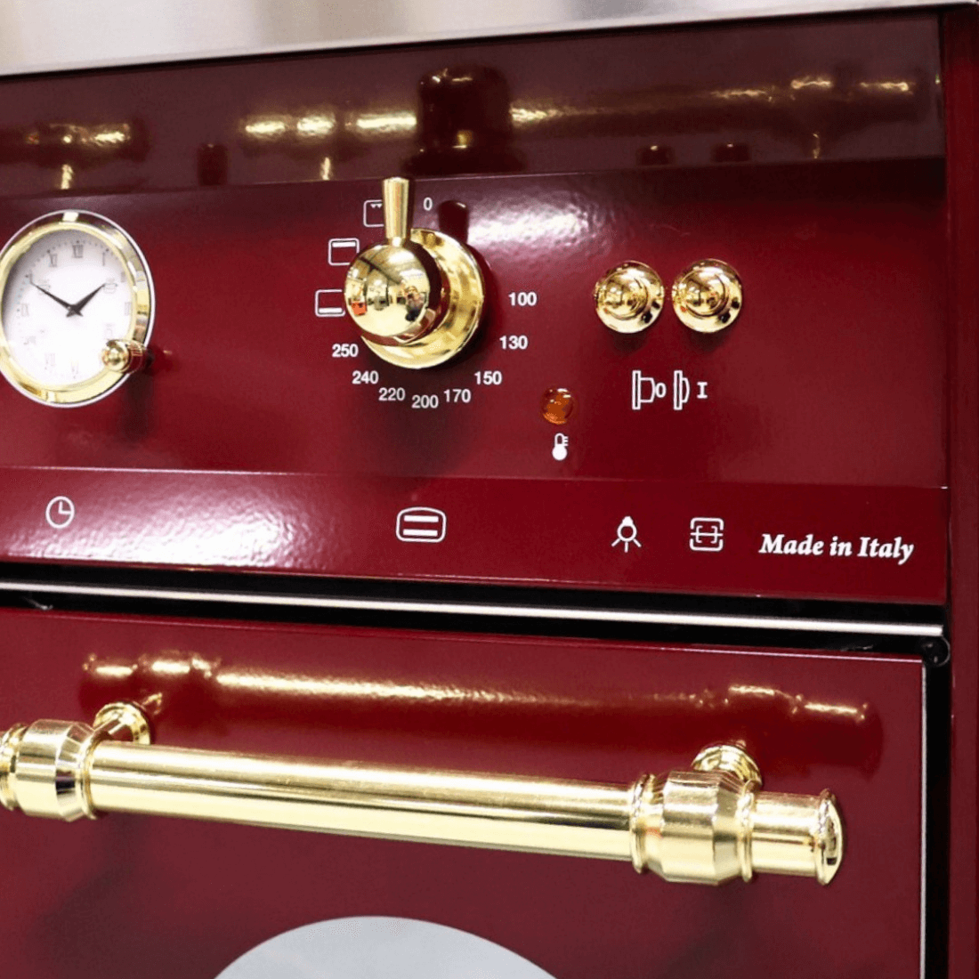 Detalhe do fogão Lofra Vintage Dolcevita, painel em vinho com botões dourados e relógio, fabricado na Itália.