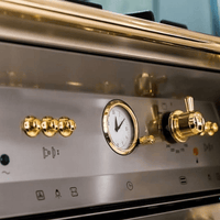 Fogão Lofra Dolcevita Inox 90cm 5 Bocas Forno Elétrico 102L — painel inox com botões e mostrador analógico dourado, estilo profissional