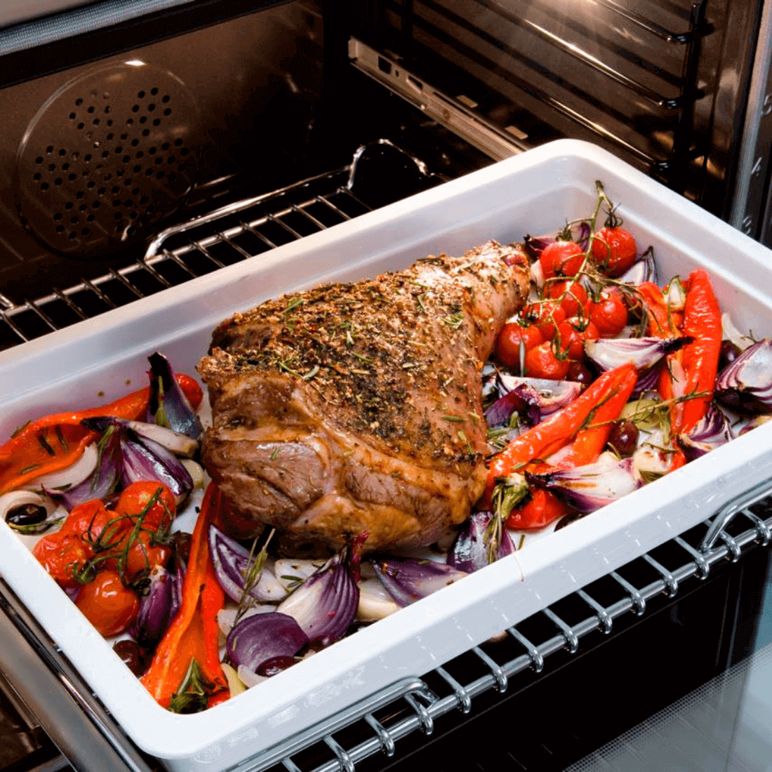 Carne assada com legumes coloridos no forno a gás Bertazzoni, ideal para refeições deliciosas.