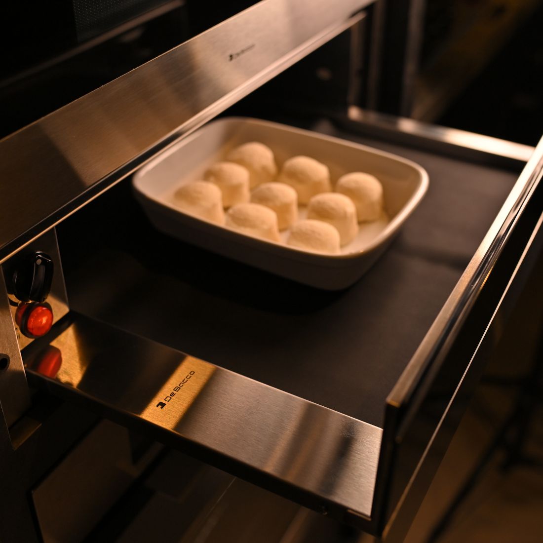 Gaveta Aquecida Debacco Montreal Inox e Vidro 60cm em inox com vidro, puxador integrado, painel e instalação de embutir mostrando prato com pães