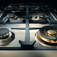 Close-up do fogão Bertazzoni com 6 queimadores a gás e trempes robustas em ferro fundido.
